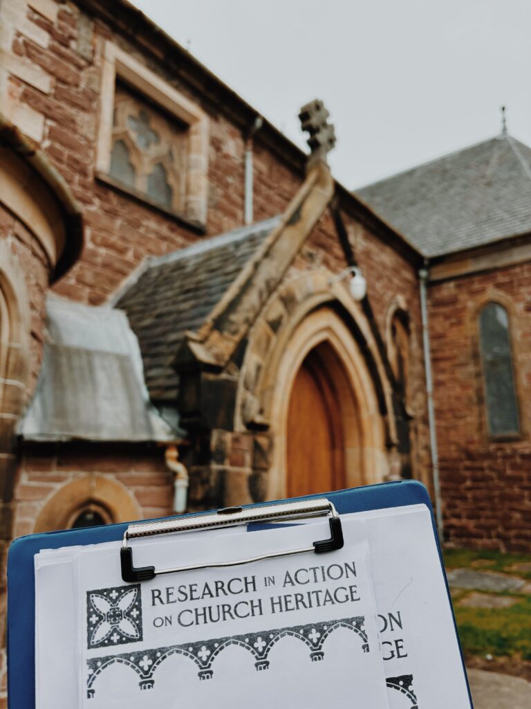 A clipboard with papers and the heading 'research in action on church heritage' in front of a door of Old High Kirk
