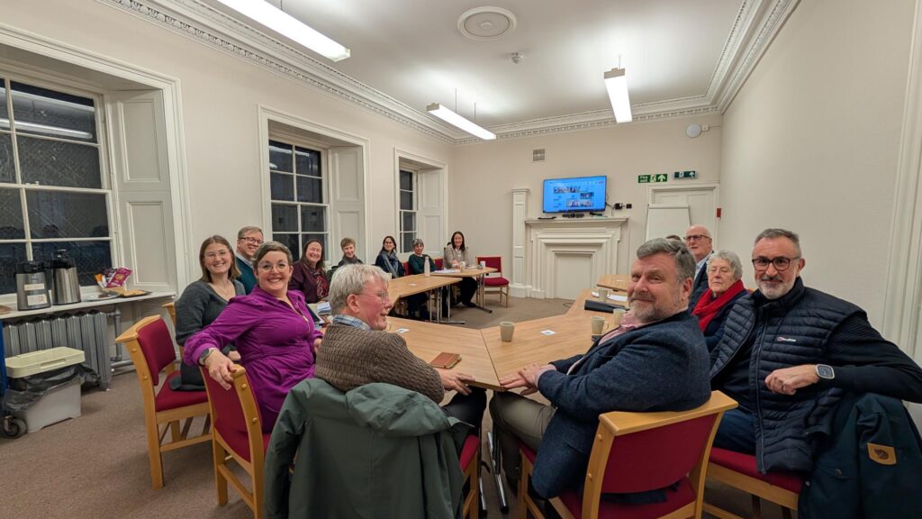 The Heritage Action group members sitting round a table at the meeting, smiling at the camera