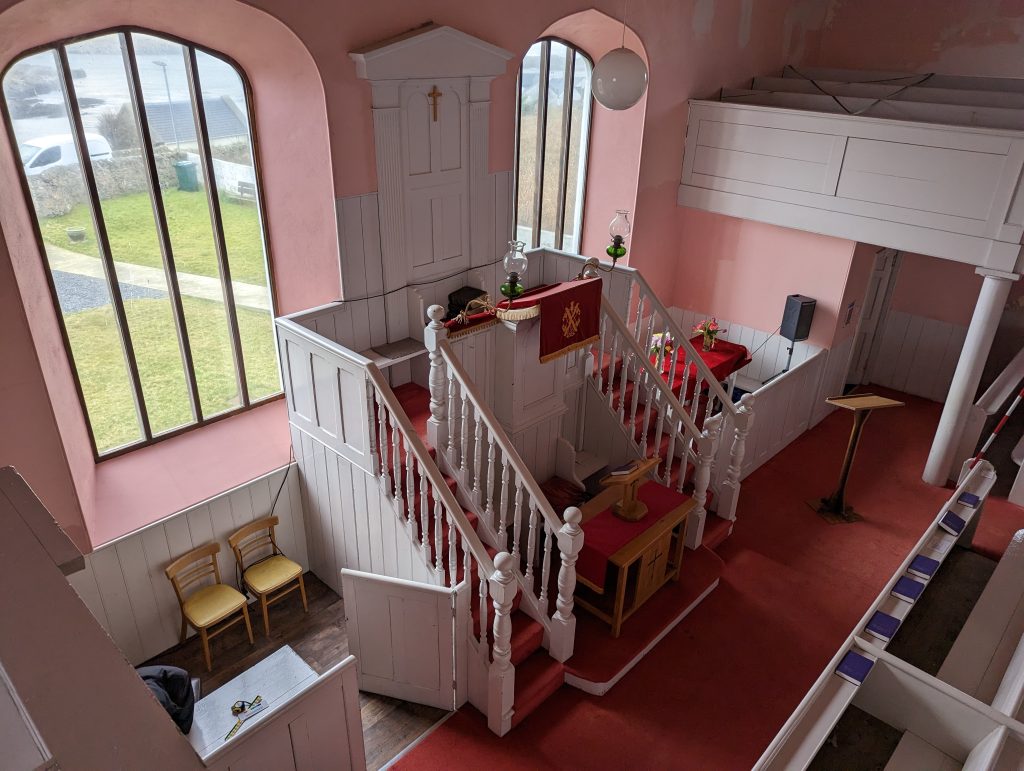 Interior photograph from the balcony showing the raised pulpit of the church