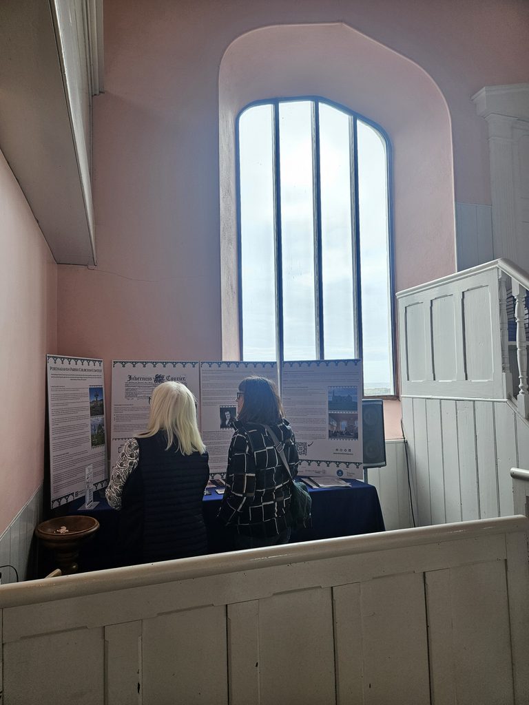 Two visitors reading information boards at Portnahaven Church
