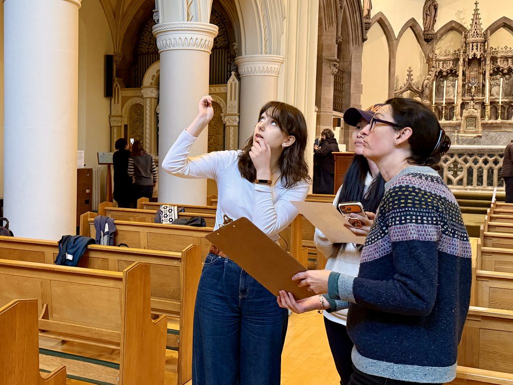 Volunteers discussing recording aspects of the Gillis Centre, pointing at the ceiling and holding clipboards